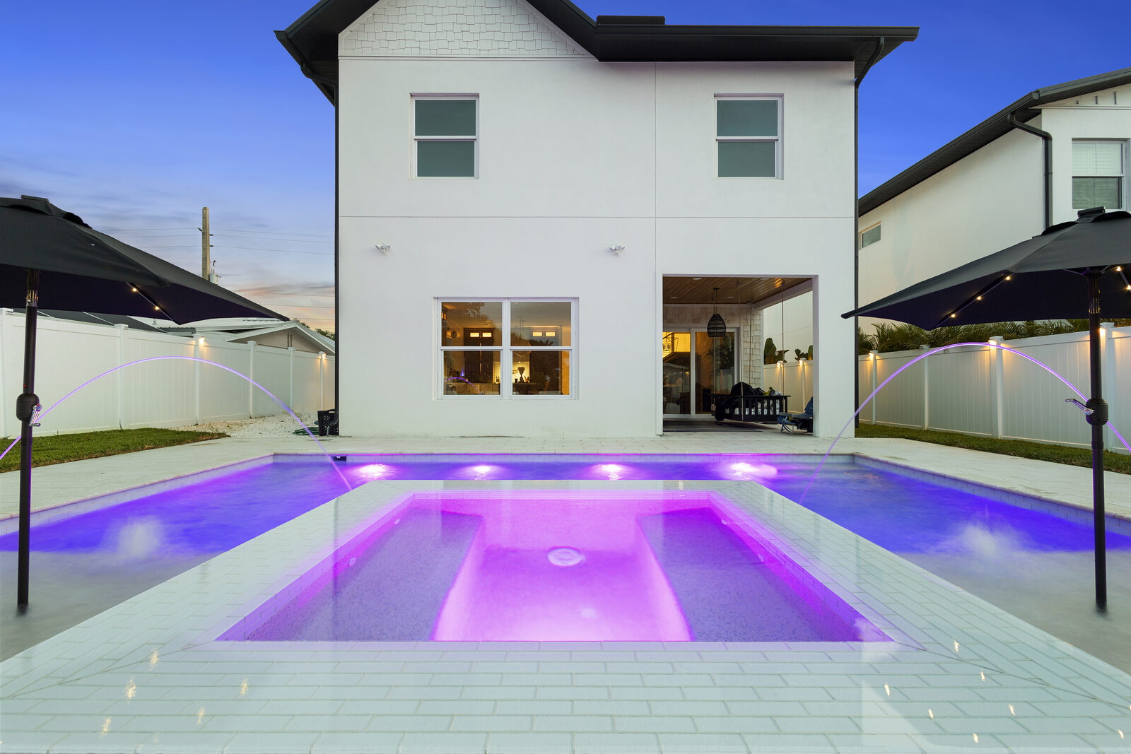Modern home with a color-lit pool at twilight