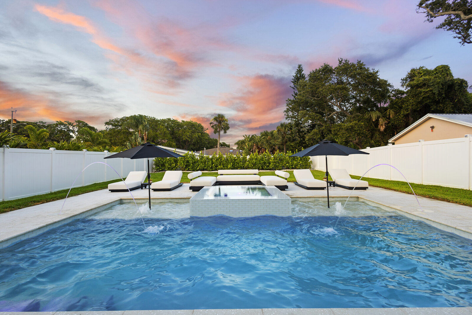 Backyard pool at twilight with a pink sky